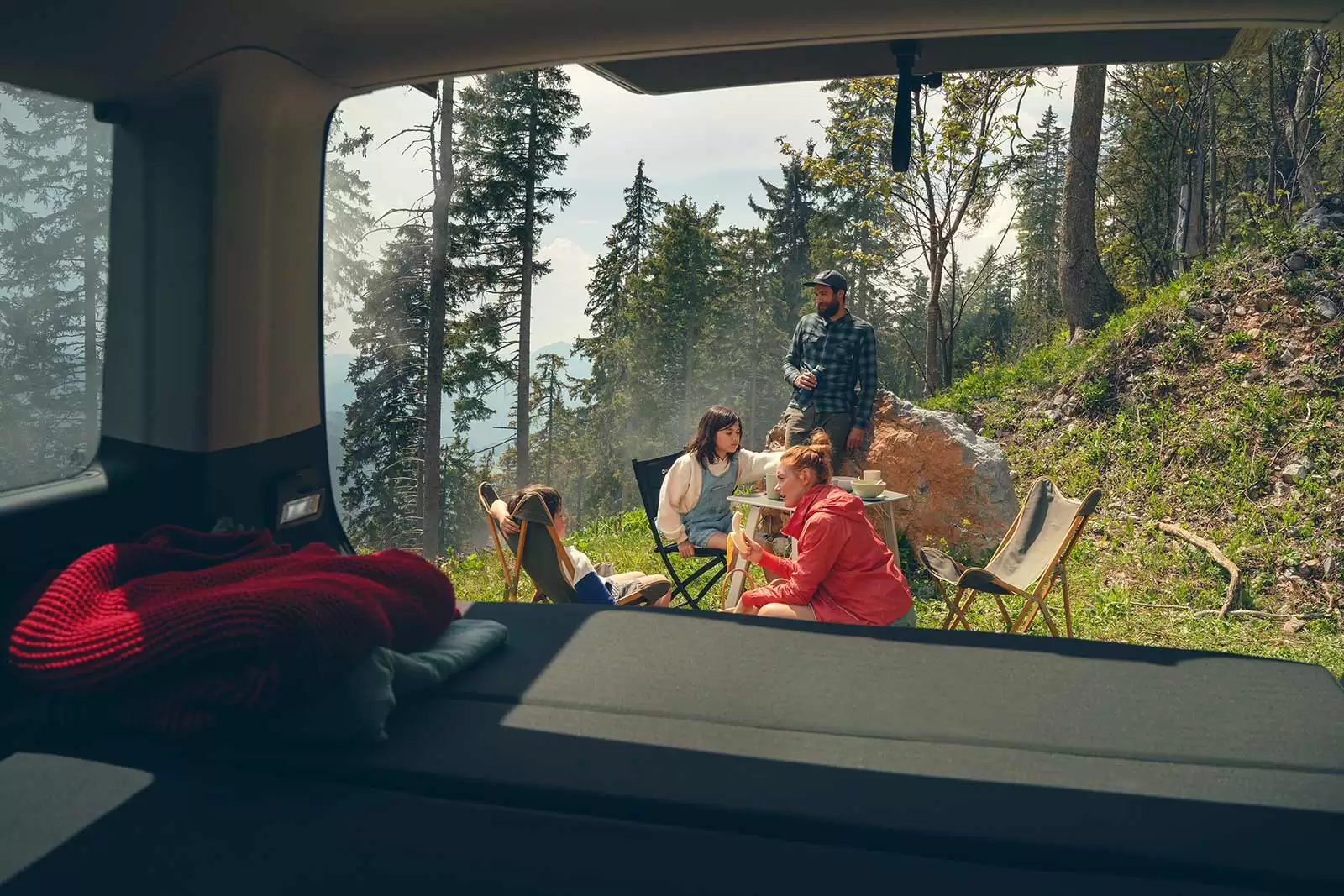 familie-macht-auf-campingsitzgruppe-hinter-dem-multivan-pause