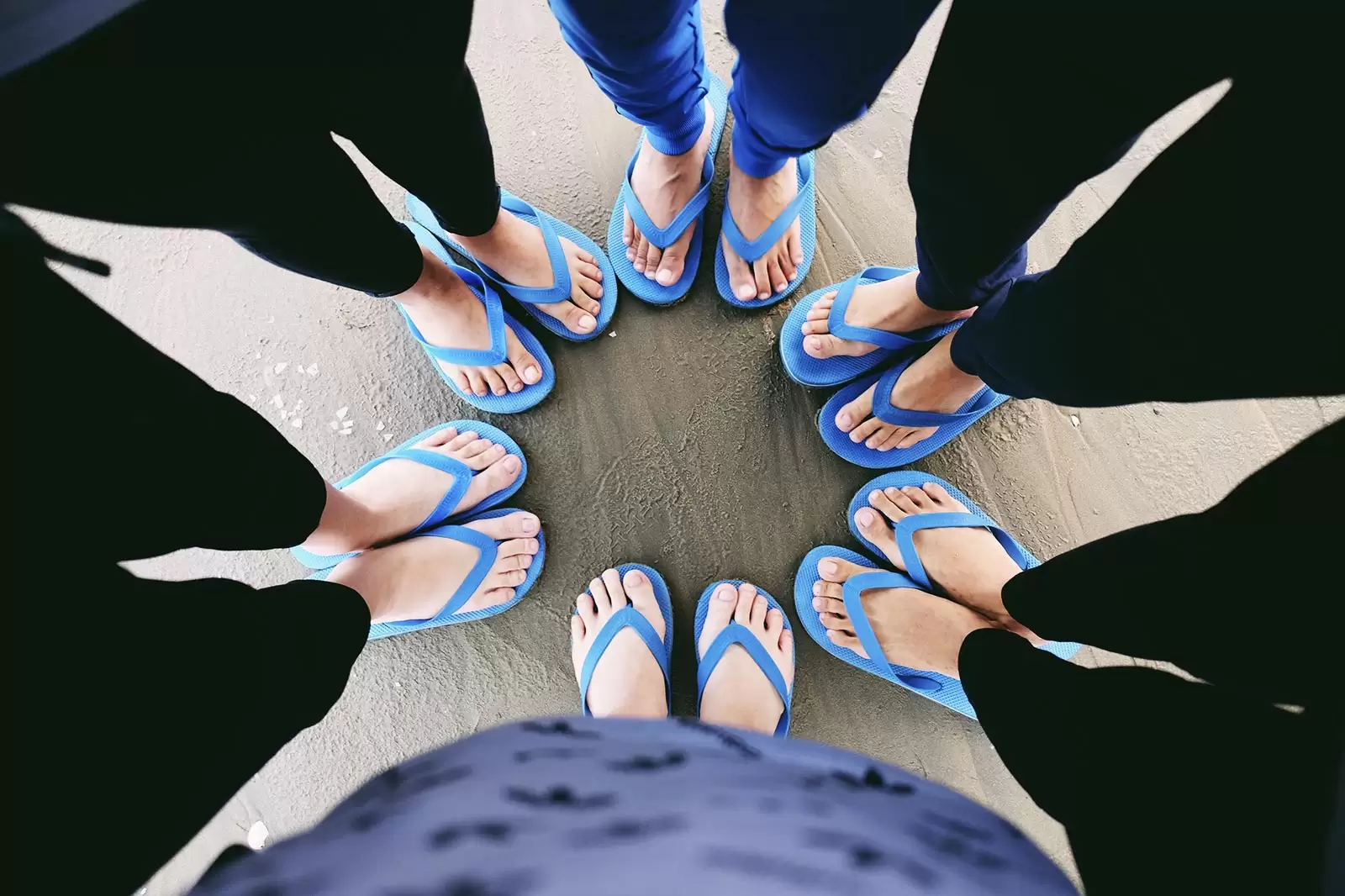 personen-mit-blauen-flip-flops-stehen-im-kreis-am-strand