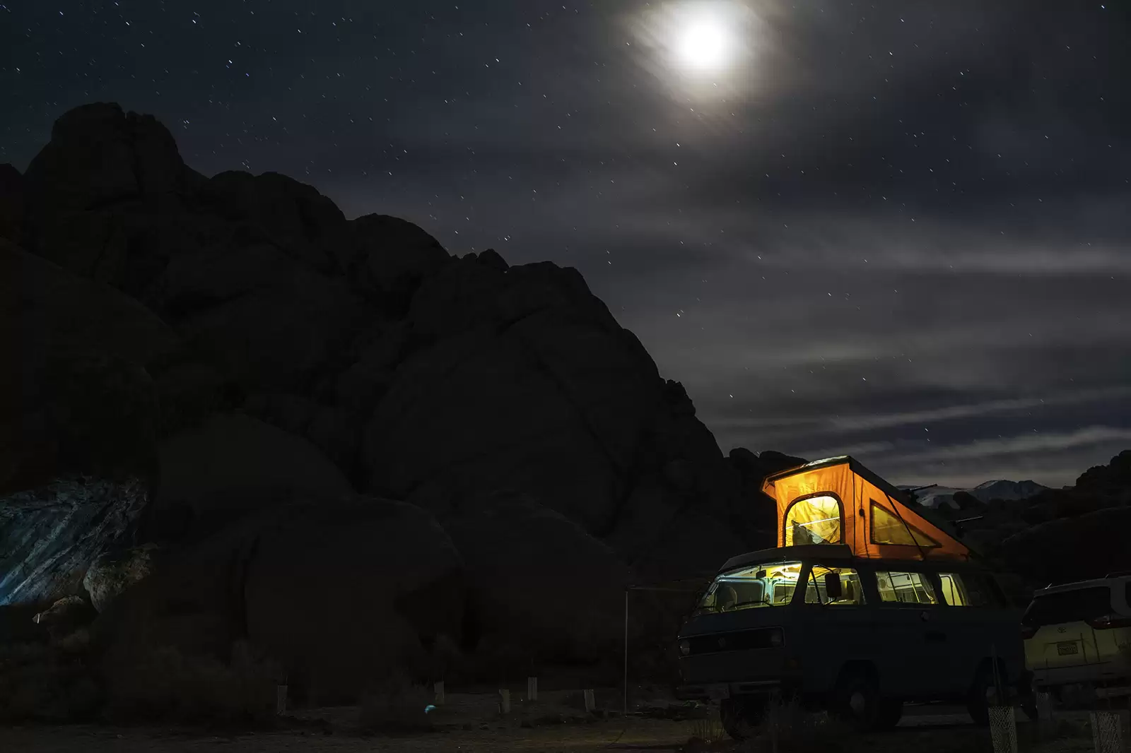 camper-mit-beleuchtetem-aufstelldach-bei-nacht-in-mondschein