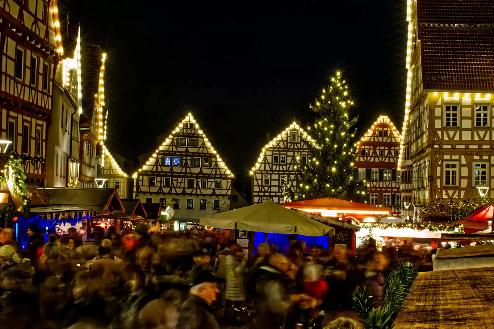 beleuchteter-weihnachtsmarkt-mit-vielen-menschen-und-ständen